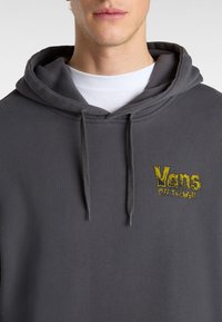 Gray hoodie made of soft fabric featuring adjustable drawstrings, a kangaroo pocket, and a yellow embroidered "Vans Off The Wall" logo.