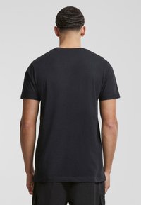 Zwarte katoenen t-shirt met een ronde hals, korte mouwen en een relaxte pasvorm. Gladde textuur, geen zichtbare logo's of patronen op de achterkant.
