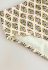 Material textil cu un model de frunze verzi și bleumarin pe un fundal roz deschis, cu o textură netedă și o margine cusută.