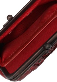 Rote Stofftasche mit strukturiertem Oberflächen, Metallrahmen und Klappverschluss. Das Innere verfügt über gefütterte Fächer aus passendem roten Stoff.