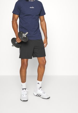 Marineblauw T-shirt met logo, zwarte shorts, een halter vasthoudend. Witte sportschoenen met grijze accenten, gecombineerd met witte sokken. Minimalistisch ontwerp.