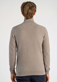 Grå stickad tröja med hög krage, med ett strukturerat mönster, långa ärmar och ribbade muddar och nederkant.