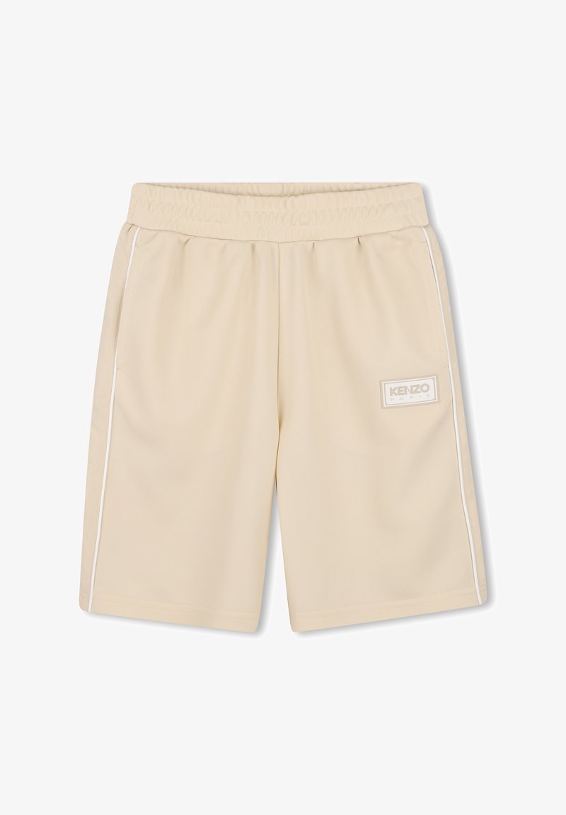 Shorts de sport beiges en tissu texturé, dotés d'une taille élastique, de rayures blanches latérales et d'un écusson logo sur le côté gauche.