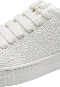 Scarpa da ginnastica bianca con tomaia testurizzata a puntini in rilievo, lacci piatti e suola in gomma solida con motivo a onda lungo il bordo.