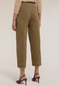 Pantalones de pierna ancha color caqui con una cintura alta, dos bolsillos traseros y detalles de panel en las rodillas. La tela es suave con costuras visibles.