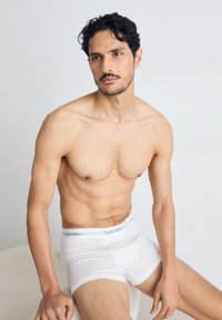 Boxer-briefs blancs en coton de Calvin Klein, avec une taille douce. Le tissu est lisse avec un léger élasticité, ajusté autour des cuisses.