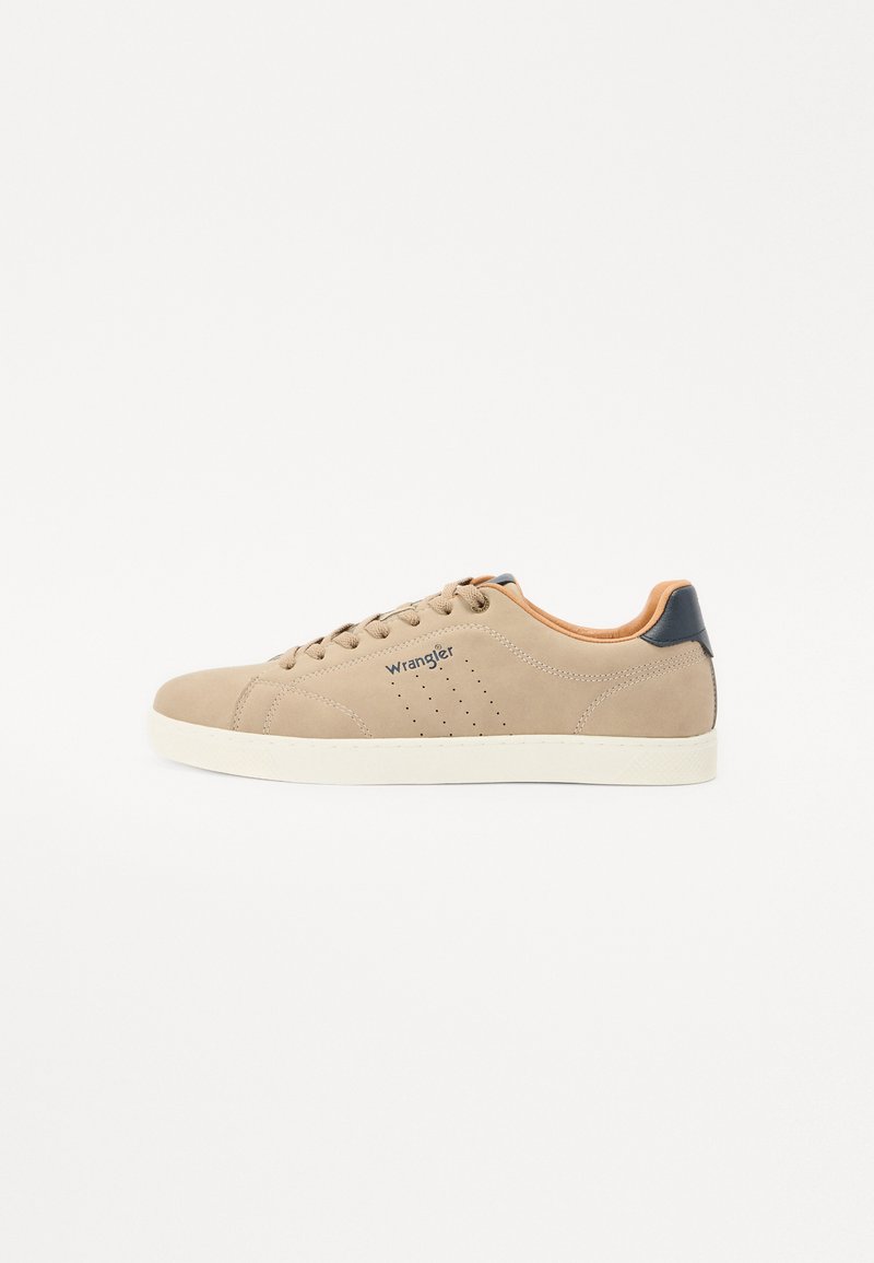 Beige suede sneaker with a white rubber sole, featuring round toe, lace-up front, and a navy heel accent. "Wrangler" logo on the side.