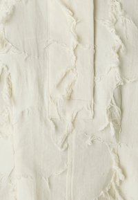 White fabric with frayed edges and patches. Soft texture with varying patterns of roughness and smoothness. Minimalistic design.