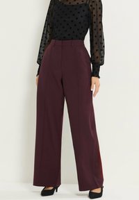 Wijdvallende broeken in diep burgundy stof met een gladde textuur en een gepaste pasvorm, met een hoge taille en voorzichtige vouwen.