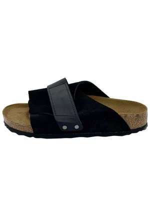Black suede sandal featuring a wide strap with a textured leather accent, cork footbed, and rubber sole with a wave pattern.