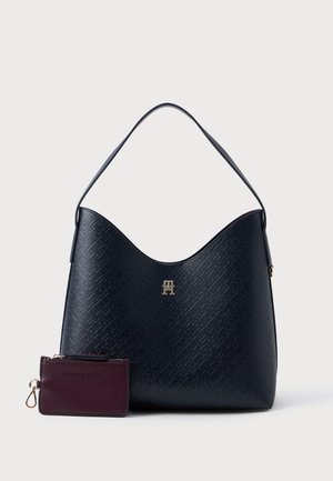 Hobo taske i struktureret mørkeblå materiale med et guld logo. Inkluderer et lille bordeaux kortholder med lynlås og en nøgleringevedhæftning.