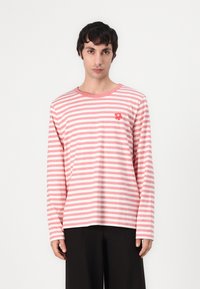 Rožių ir baltos spalvos dryžuotas marškinėliai ilgomis rankovėmis pagaminti iš medvilnės, su apvalia iškirpte ir mažom raudonom gėlių siuvinėtomis detalėmis ant krūtinės.