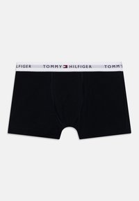 Melni kokvilnas bokseršorti ar baltu elastīgu jostasvietu, uz kuras ir "TOMMY HILFIGER" zīmols un sarkans un zils logotipa akcenti.