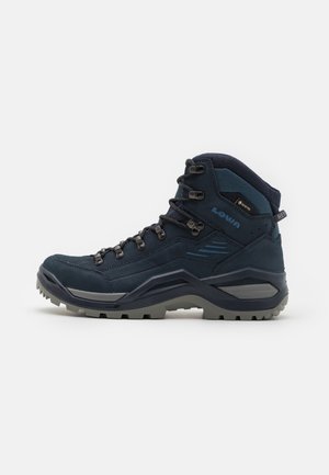 Bota de caminhada azul escura com camurça e rede, superfície texturizada, sistema de atacadores proeminente, sola de borracha e detalhe do logótipo na lateral.