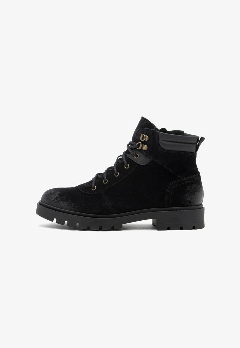 Botas negras hasta el tobillo hechas de ante y cuero, con ojales de metal, una parte superior texturizada y una suela de goma resistente con surcos.