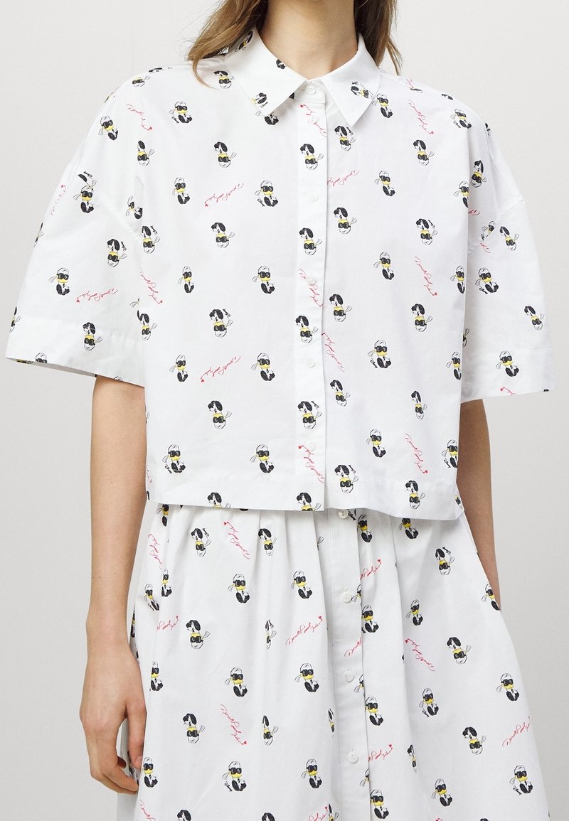 White short-sleeve button-up shirt and skirt set with black-and-white dog faces wearing sunglasses and red cursive text print.