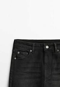 Svarta jeans i denim med knäppning, fem fickor och subtila blekningar. Tyget är slätt med en robust finish.
