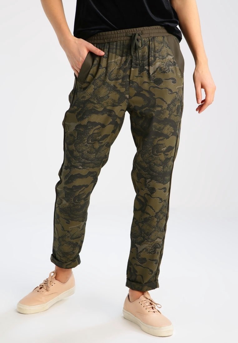 Pantalons de jogging à motif camouflage en olive, avec une taille élastique, des poches latérales et des poignets resserrés, associés à des baskets légères.