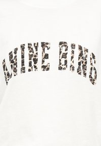 Κείμενο "WINE BING" με κεφαλαία γράμματα και μοτίβο λεοπάρδαλης σε λευκό φόντο.