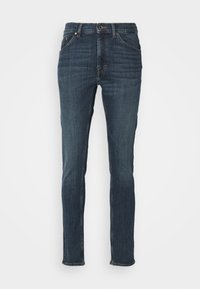 Mörkblå slim-fit denim jeans med framfickor och knappt stängning, uppvisade på en neutral vit bakgrund.