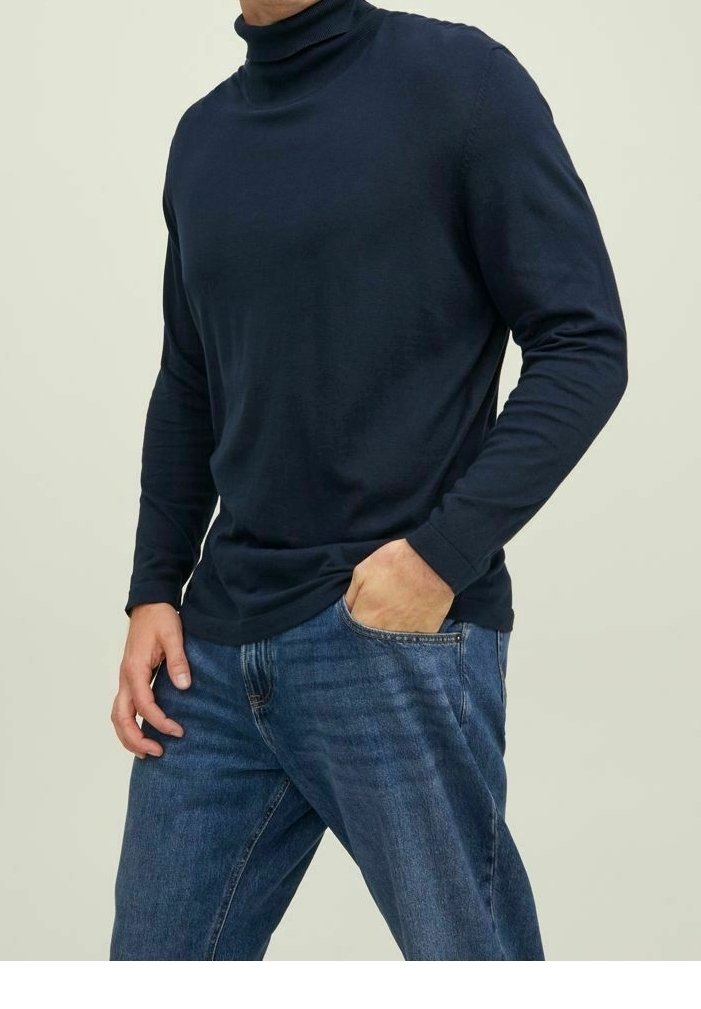 Maglione a collo alto blu navy con maniche lunghe, realizzato in un tessuto liscio. Indossato con jeans in denim blu chiaro, con una vestibilità comoda e tasche.