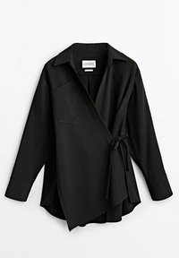 Musta kietaisupaita, joka on valmistettu sileästä kankaasta. Paidassa on kaulus, yksi rintatasku ja vyötäröllä solmuseikka. Pitkät hihat, joissa on kalvosimet.