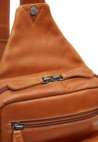 Borsa a tracolla in pelle marrone con una texture liscia, dotata di chiusura superiore con zip e dettagli in metallo. I dettagli cuciti ne migliorano la durata.
