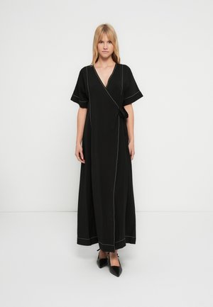 Svart omslagskjole laget av lett stoff, med korte ermer, v-hals, hvite søm-detaljer og et knytebelte i midjen.