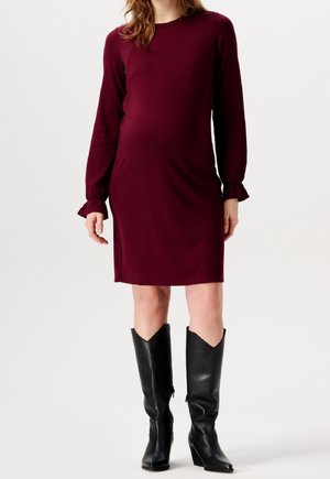 Burgundy pitkähihaine mekko, jossa on rento leikkaus ja frillatut hihansuut. Yhdistetty teräväkärkisten mustien nahkasaappaiden kanssa. Sujuva kankaan rakenne.