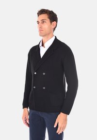 Cardigan nero a maglia con doppio petto, tessuto testurizzato, rever a scadere, due tasche frontali e chiusure con bottoni neri.