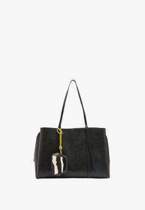 Czarna skórzana torba typu tote z dwoma paskami na ramię oraz czarno-biały futrzany brelok w paski przyczepiony żółtym sznurkiem.