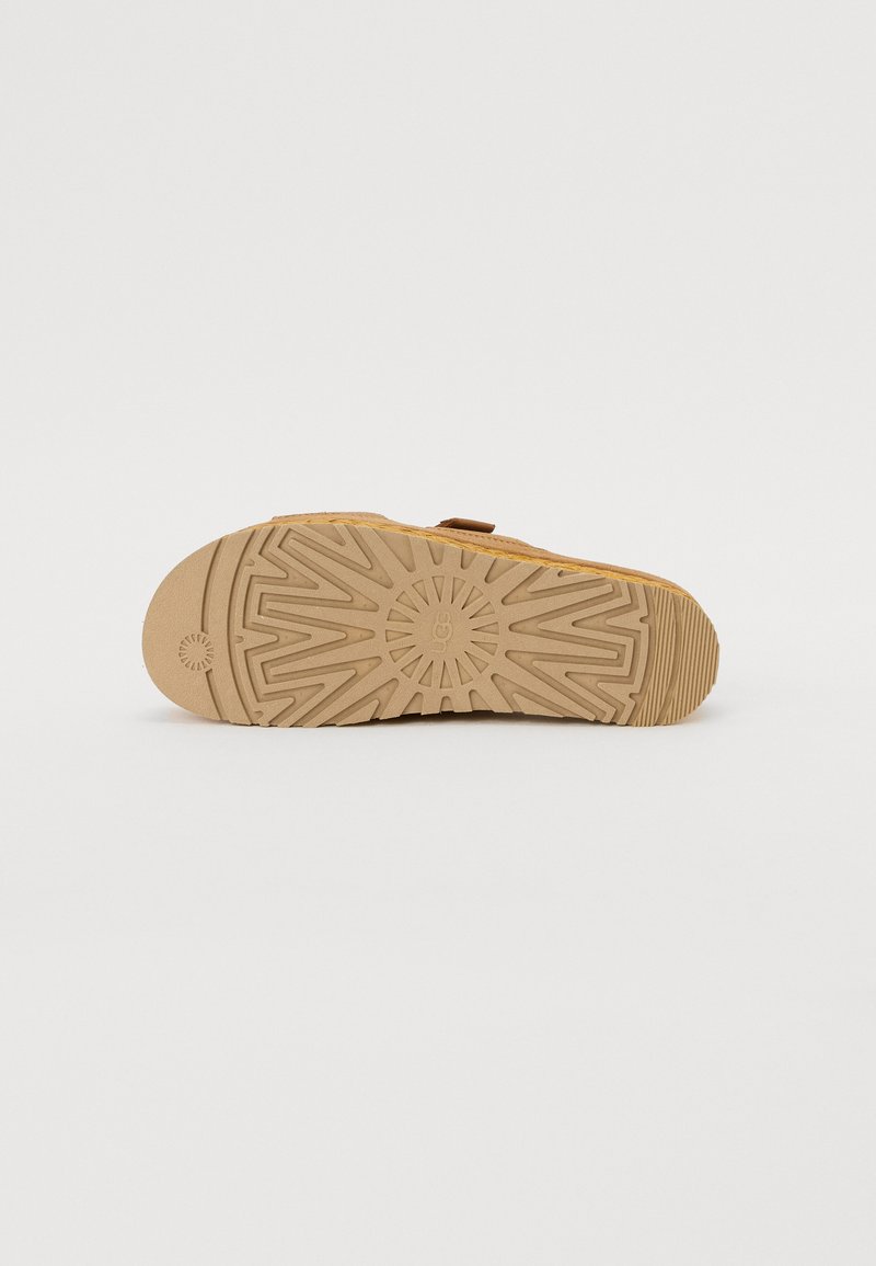 Sandaal met een gestructureerde tan bovenkant en een stevige rubberen zool met een geometrisch patroon voor grip. Verstelbare band voor een veilige pasvorm.