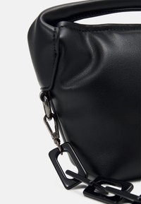 Czarna skórzana torebka o miękkiej fakturze, z zaokrąglonym kształtem, metalowym łańcuszkiem i zapięciem na zatrzask.