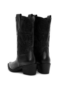 Botas de vaquero de cuero negro con detalles de costura lateral, punta afilada y tacón bajo. Presentan un embossing decorativo de flores en los lados exteriores.
