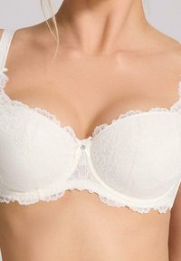 Biały koronkowy biustonosz o półuszczelnionym kroju, zdobiony kwiatowymi wzorami, delikatnym koronkowym wykończeniem oraz małym akcentem w postaci klejnotu na środku.