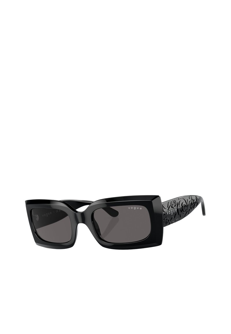 Occhiali da sole neri rettangolari con lenti scure. Presentano una forma unica a occhio di gatto e temple decorati con un motivo nero. Logo sulla lente destra.