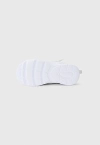 Semelle de sneaker blanche avec un motif de semelle texturé, dotée d'un matériau en caoutchouc lisse et d'une petite boucle à l'arrière pour un enfilage facile.