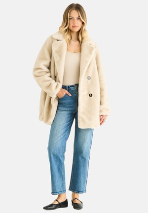 Beige faux fur coat with a notched collar, two black button closures, side pockets, paired with blue straight-leg jeans and black flats.