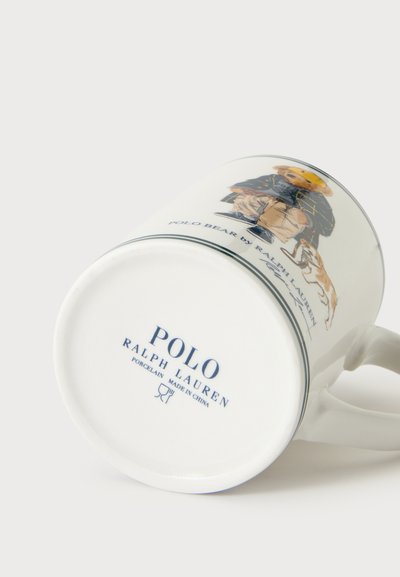 Tasse en porcelaine blanche Polo Ralph Lauren avec illustration d'ours en peluche et de chien, affichant le texte de la marque et les détails de fabrication au fond.