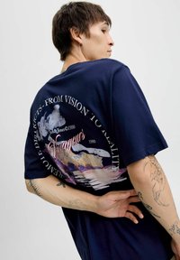 Granatowa bawełniana koszulka z kolorową grafiką na plecach, w tym góry i napis "Voyageurs" w różowym cursive.