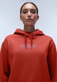Rode hoodie van katoen, met een textuurlogo op de voorkant en bijpassende trekkoorden. Zacht, casual ontwerp.