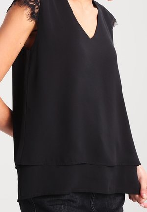 Zwarte mouwloze blouse met een V-hals, gelaagd ontwerp en delicate kanten afwerking op de schouders. Soepele stof met een vloeiende silhouet.