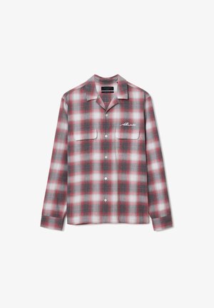 Red and gray plaid flannel shirt with long sleeves, two chest pockets, button closure, and an embroidered logo on the left side.