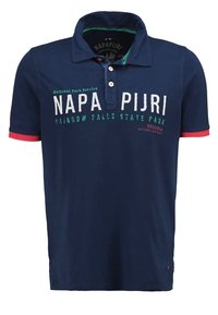Polo shirt bleu marine avec col, arborant un text blanc et vert. Accents rouges sur les manches. Matière en coton avec une texture lisse.