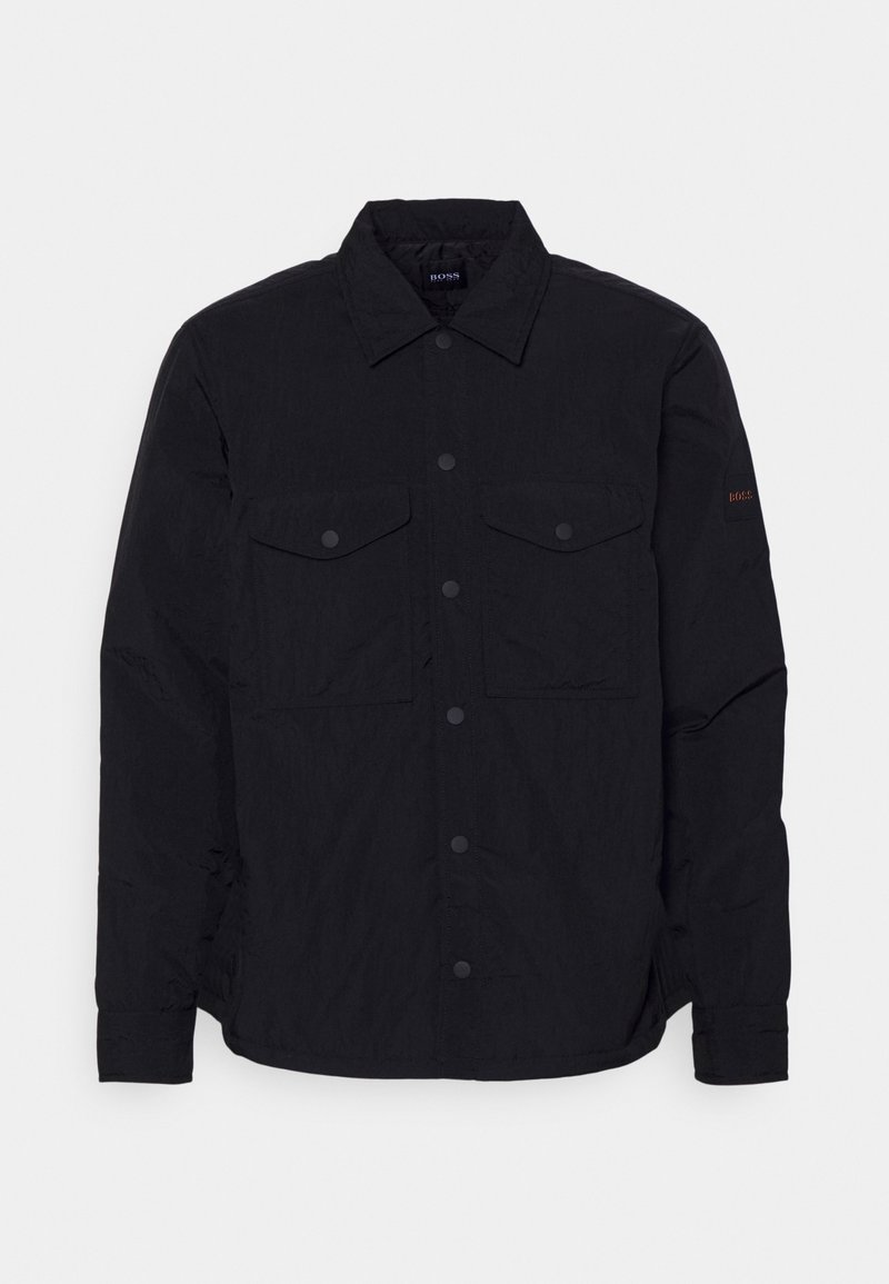 Černá košile na knoflíky z lehké látky. Má dvě náprsní kapsy, límec a jemné logo na rukávu. Strukturální povrch.