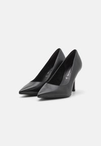Tacchi alti in pelle nera con punta affusolata, texture liscia e tacco a stiletto sottile. L'interno ha un rivestimento morbido.