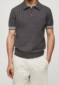 Lyhythihainen polo-paita tummanharmaana pystysuorilla raidoilla, ribbauskauluksella ja -hihoilla, joissa on valkoisia yksityiskohtia. Valmistettu tekstuurilla varustetusta neulekankaasta.