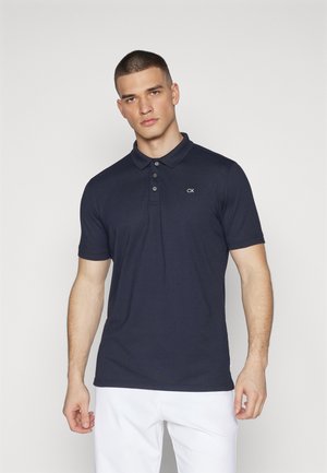 Mörkblå polo-shirt med krage, korta ärmar, treknappsknäppning och CK-logotyp broderad på bröstet. Slät tyg.