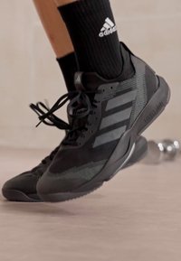 Czarne buty sportowe z siateczkową cholewką, teksturowanym wzorem i trzema czarnymi paskami. Posiadają wygodną podeszwę i czarne sznurowadła.