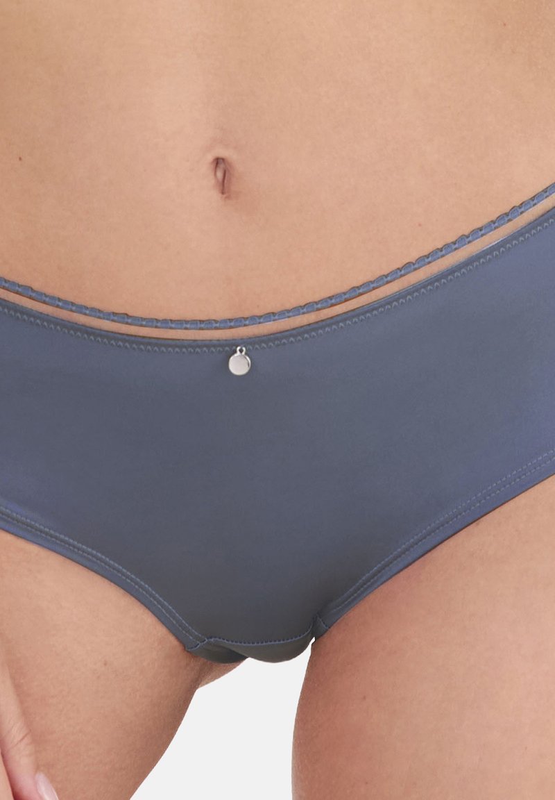 Sivé hipsterské spodné prádlo s hladkou textúrou a tenkým dekoratívnym pásom. Obsahuje malý kovový šperk na prednej časti v strede.